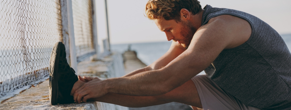 Man stretching leg by reaching for toes on elevated leg
