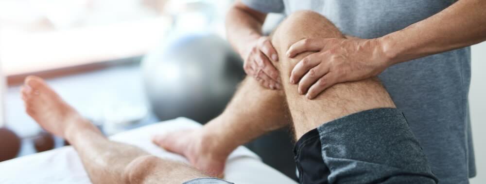 Man on doctor's table with right knee bent being examined by doctor